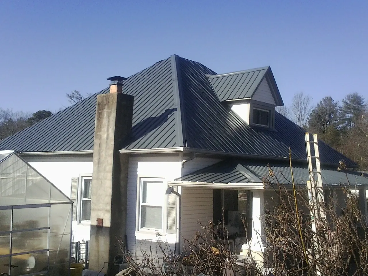 Dark blue standing seam metal roof on a white farmhouse with dormer — Slate & Tile Roof Repair by Roofing Brothers in Detroit Lakes