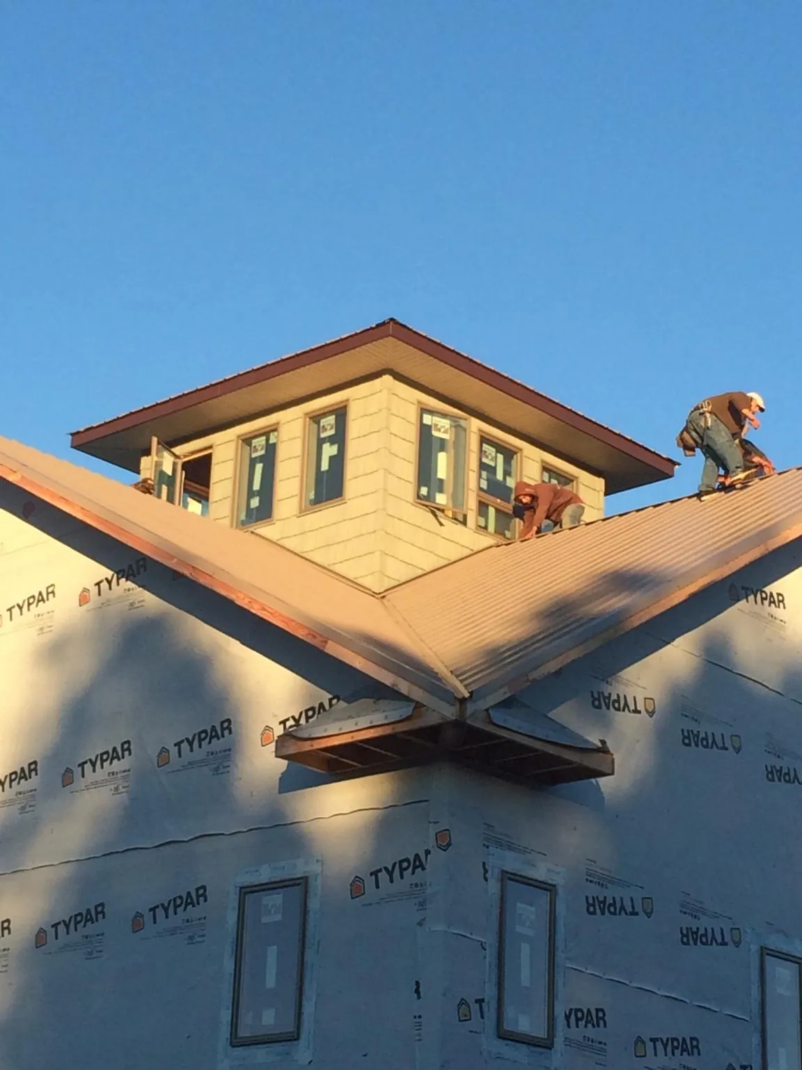 Roofers working around a rooftop cupola on a new metal roof at sunset — Roof Waterproofing in Detroit Lakes by Roofing Brothers